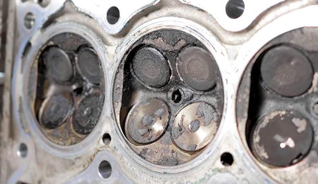 Soupapes et chambres de combustion fortement calaminées sur un moteur essence
